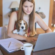 Student working on computer with a dog on her lap