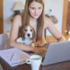 Student working on computer with a dog on her lap